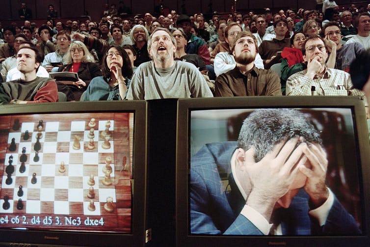 Man holds head in hands before enthralled audience.