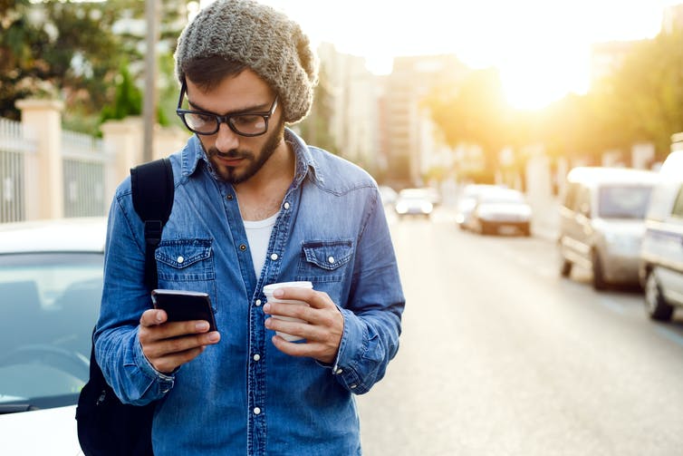 Young man on his phone with a coffee.