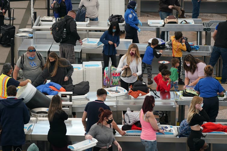 Travellers wearing face masks while pass through an airport security checkpoint.