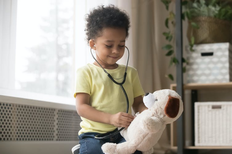 Young boy playing with a stethoscope listens to teddy's chest