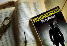 Frankenstein novel seen with a clock and against printed pages.