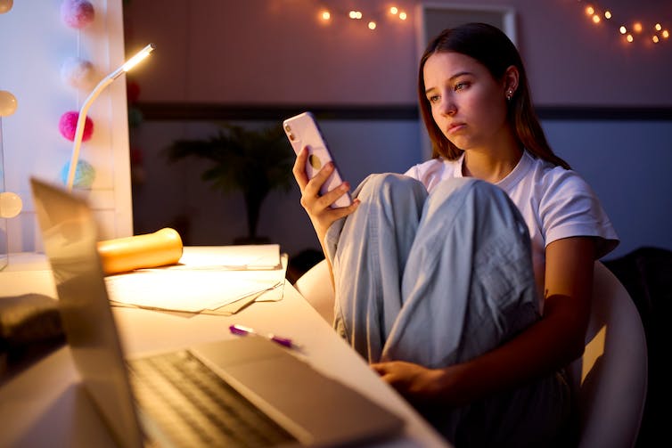 Girl looks at her phone while sitting at her desk