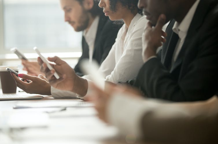 Row of colleagues using their phones.