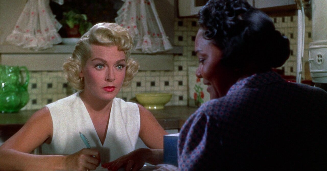 Lora (Lana Turner) and Annie (Juanita Moore) sitting across from each other at a dinner table in Imitation of life (1959).